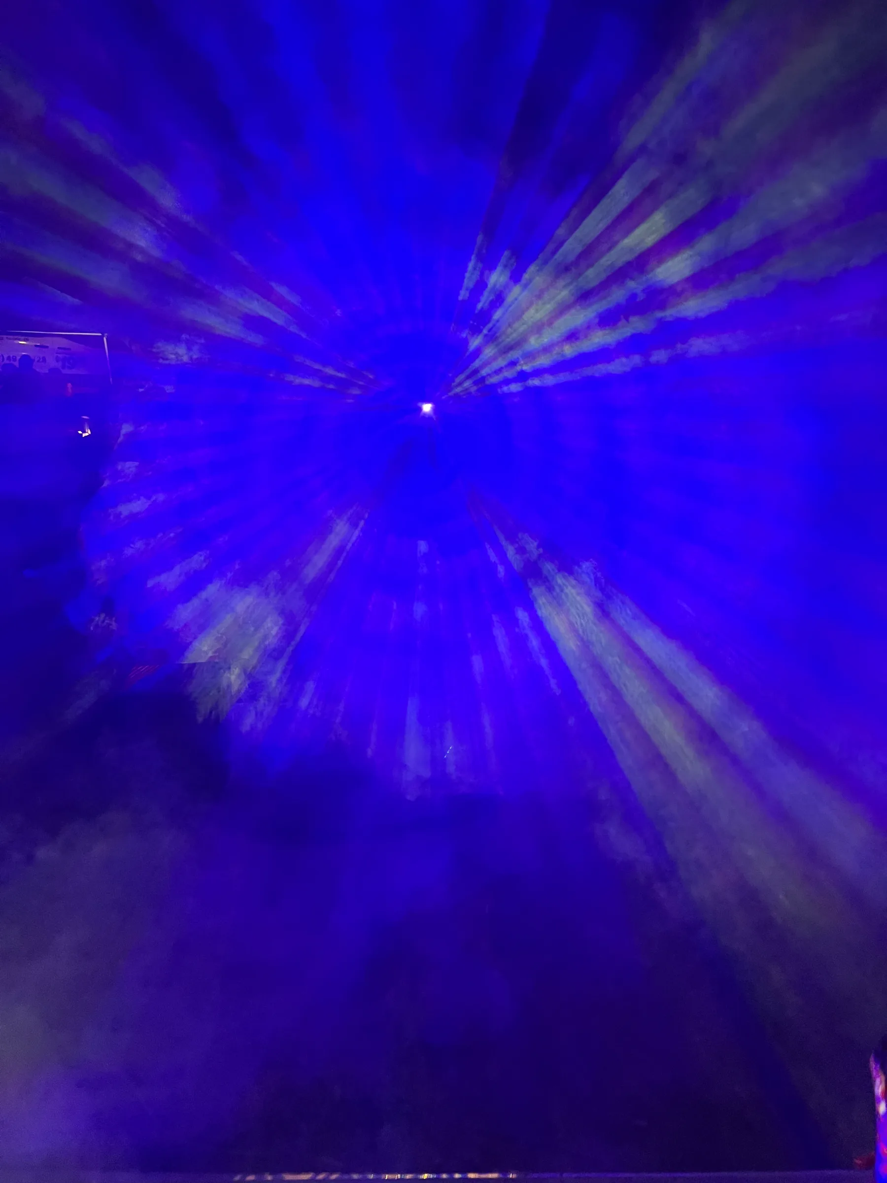 Deep blue light rays radiate from a bright central point through thick fog.